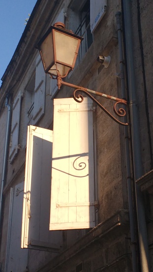 Lantern casting shadow on shutters at sunset in France