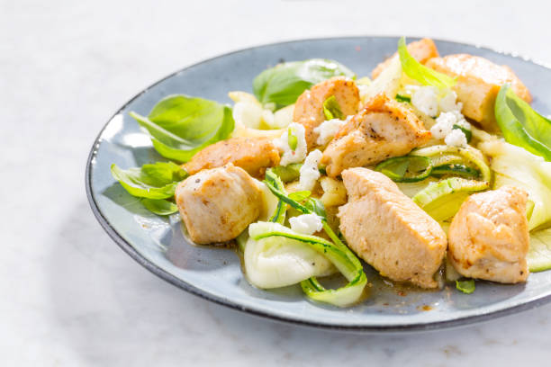 Low carb zucchini pasta with chicken Healthy low carb food. Zucchini zoodles noodles spaghetti pasta with fried chicken chunks and cheese on plate. Closeup. feta cheese block stock pictures, royalty-free photos & images