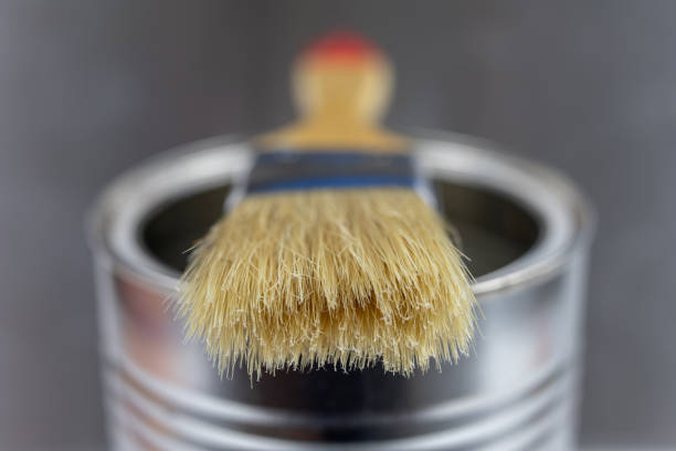 istock A paint brush and a can of paint on a workshop table. Painting accessories for construction workers. Light background. 1059657994