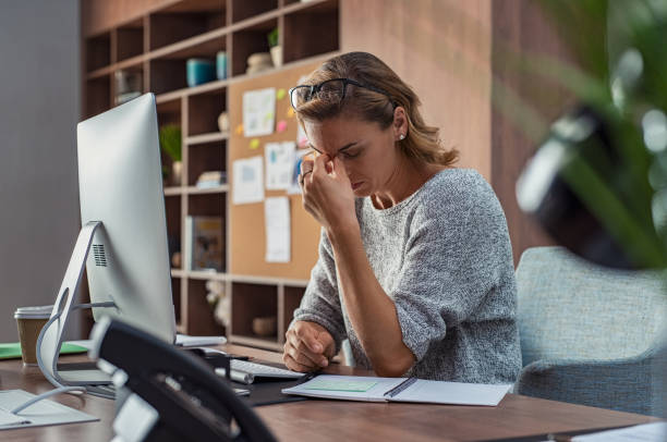 femme d’affaires ayant des maux de tête au bureau - mains devant les yeux photos et images de collection