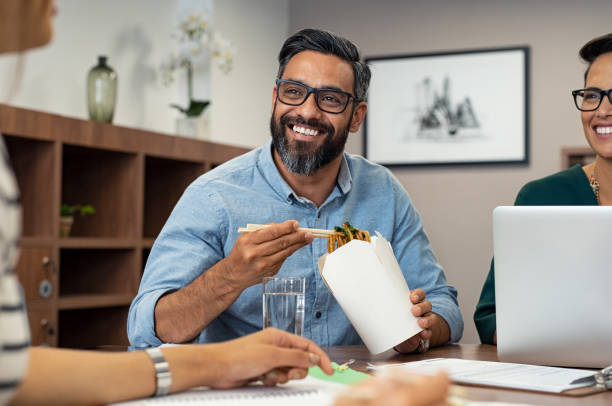 hombre de negocios comer fideos durante almuerzo - lunch business office business lunch fotografías e imágenes de stock