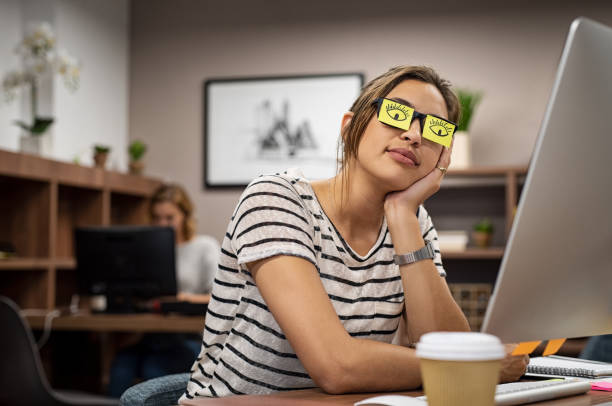 Tired woman covering eyes with post it Sleeping businesswoman covering her eyes with sticky notes on eyeglasses. Young casual woman rest with eyes drawn on adhesive notes at creative office. Girl leaning face on hand covering specs with open eye sticky notes. overworked funny stock pictures, royalty-free photos & images