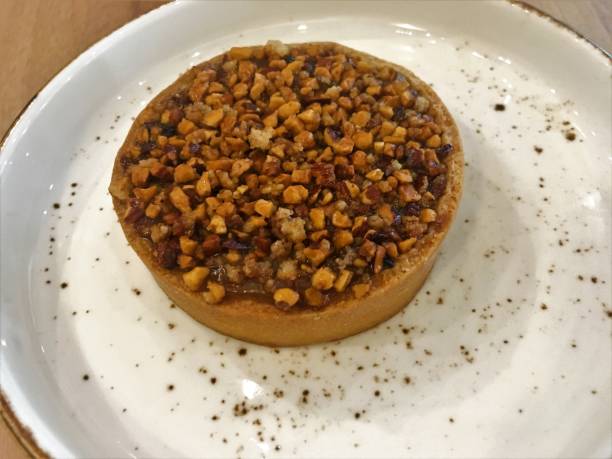 istock Caramel tart with caramelized nuts on white plate wooden table. 1059664070