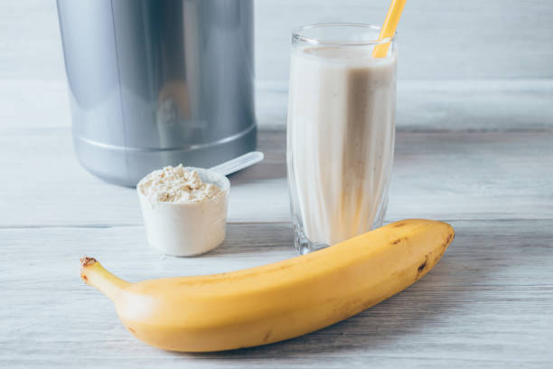 glass of whey protein shake next to measuring scoop of powder - body building milk shake protein drink drink imagens e fotografias de stock