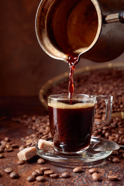 istock Black coffee is poured into a small glass cup from a copper coffee maker. 1059674794