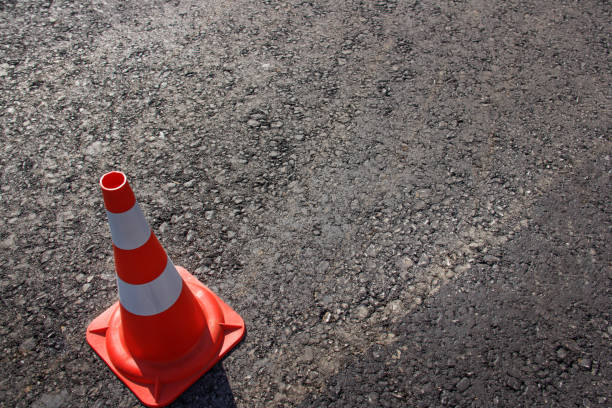 istock traffic cone, with white and orange stripes on gray asphalt, copy space 1059675656