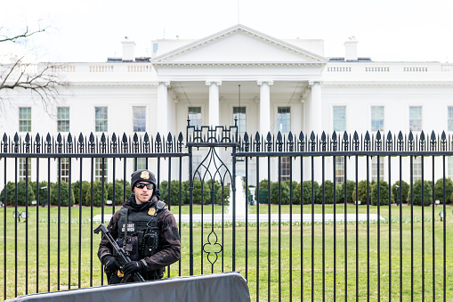 Washington DC, USA - March 9, 2018: One Secret Service security, police man guard happy standing, people by White House President building in capital city of United States in winter, spring