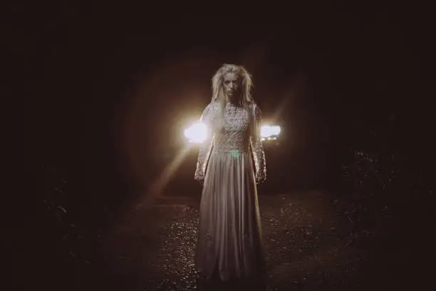 One woman, she masked herself in a scary witch for halloween, standing in front of a car.