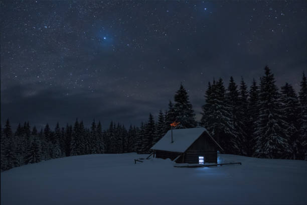 星の下での木製キャビン。家の中の窓からのライトが輝いています。冬の夜の風景です。 - sweden cottage winter snow ストックフォトと画像