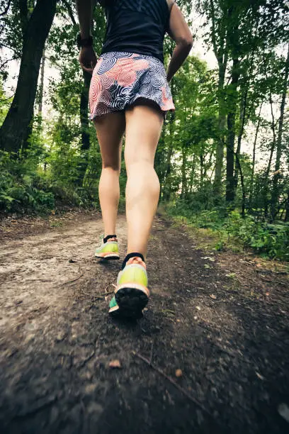Trail running athletic woman in green forest, sports inspiration and motivation. Female trail runner cross country running. Fitness concept outdoors in nature.