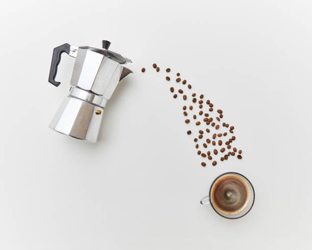 istock Coffee beans pour in a cap with drink from a metal coffee maker on a white background. Flat lay 1059718754