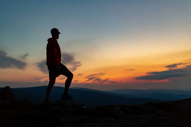 istock Man celebrating sunset looking at view in mountains 1059721998