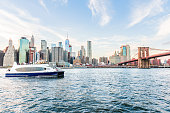 istock View of outside outdoors in NYC New York City Brooklyn Bridge Park by east river, cityscape skyline at day sunset, skyscrapers, buildings, tour boat, people, tourists 1059722098