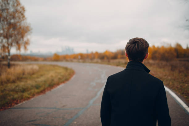 istock Young man in black coat walking on the road 1059741884
