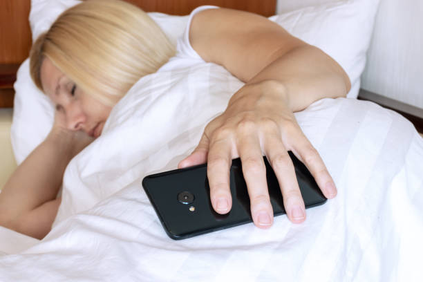 istock Blond woman sleeping in bed with a smartphone in hand 1059745730