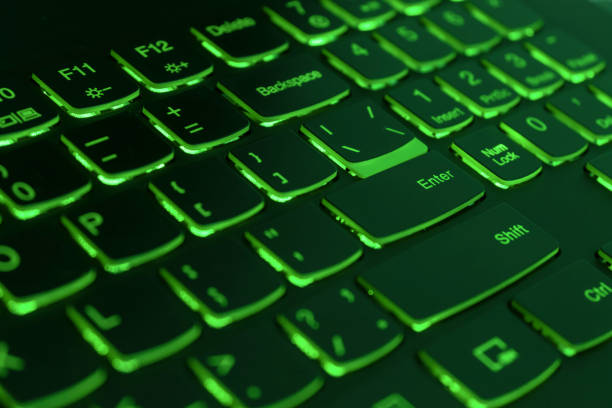 Green backlit laptop keyboard, hacking and blockchain concept.