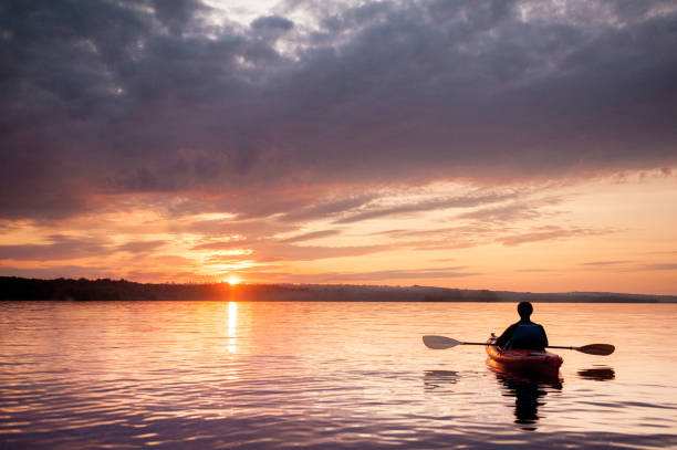 hombre en un kayak en el río en el pintoresco atardecer - kayak canoeing canoe lake fotografías e imágenes de stock