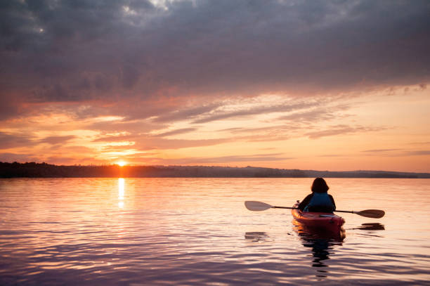 femme dans un kayak sur la rivière sur le magnifique coucher de soleil - canoë photos et images de collection