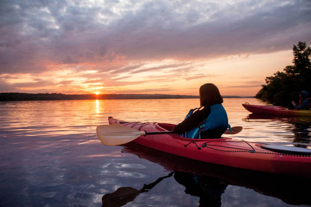 Two people in kayaks on the river on the scenic sunset Two people in kayaks on the river on the scenic sunset river swimming women water stock pictures, royalty-free photos & images