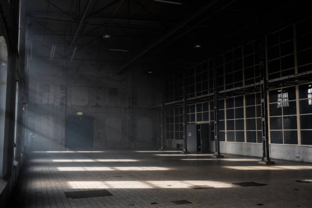 la luce del sole splende tra le finestre di un vecchio edificio di magazzini industriali abbandonato - warehouse interior foto e immagini stock