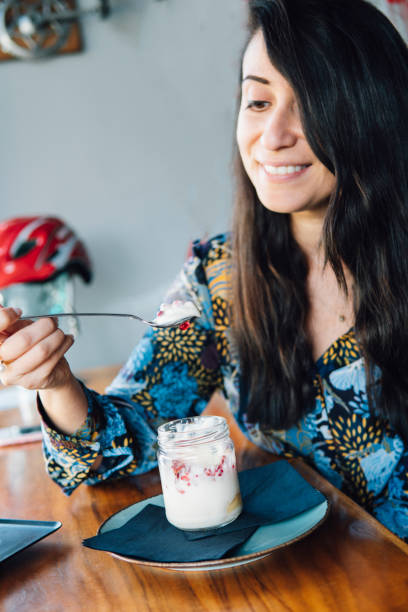 mujer comer pudín de granada en un café. - women spoon tasting elegance fotografías e imágenes de stock