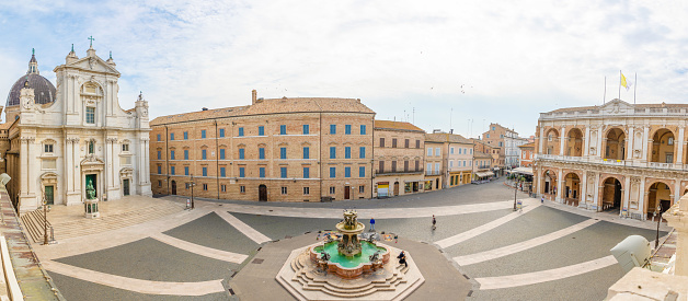 Loreto, Ancona, Italy - October 11, 2018: Square of Loreto, Basilica della Santa Casa in sunny day, portico to the side, people in the square in Loreto in Ancona, Italy