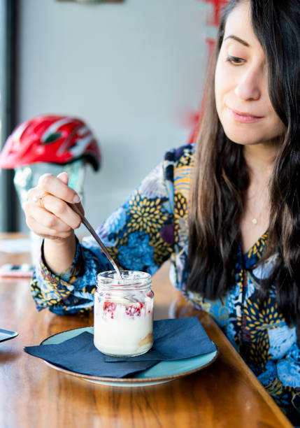 mujer comer pudín de granada en un café. - women spoon tasting elegance fotografías e imágenes de stock