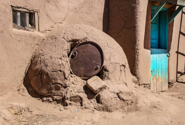 Horno - mud adobe outdoor oven in Southwestern US Pueblo community with old metal barrel top protecting the opening - common in all Spanish-occupied lands world-wide Horno - mud adobe outdoor oven in Southwestern US Pueblo community with old metal barrel top protecting the opening - common in all Spanish-occupied lands world-wide stove oven adobe outdoors stock pictures, royalty-free photos & images