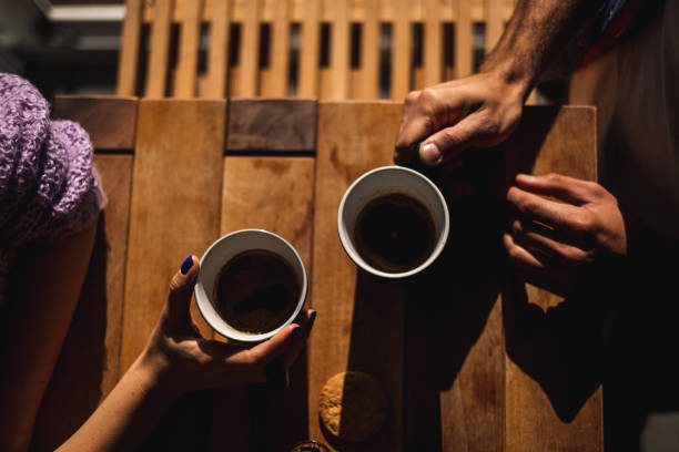 Couple holding cups of coffee on the table stock photo