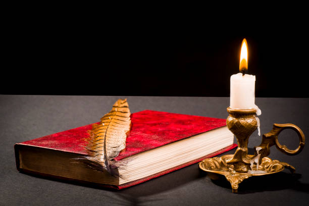 istock A pen on a book, and a lit candle in a candlestick 1059766896