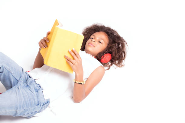 Cross-legged girl sitting on the floor reading a red book
