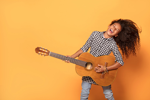 Studio shot of young  African teenage girl playing on guitar.