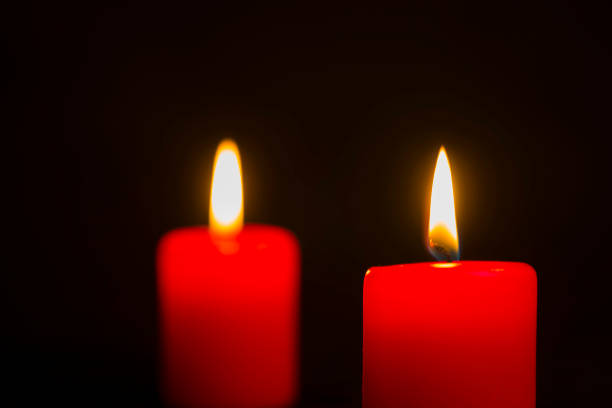 istock Two lit red candles on a black background 1059769890