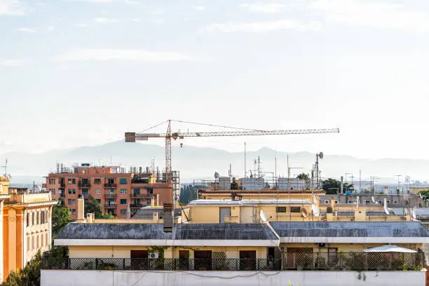 Rome, Italy historic city with mountains, cityscape skyline, high angle aerial view of urban rooftops apartment buildings, construction crane