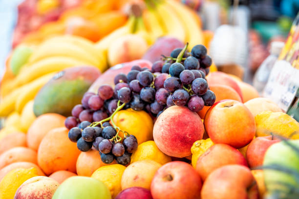 closeup of fresh ripe, purple, orange and yellow nectarines, peaches, oranges, mangoes, grapes in street market display in italy during summer - nectarine peach red market imagens e fotografias de stock