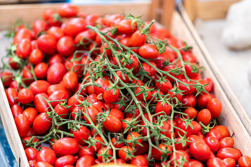 Closeup of many ripe red, small tomatoes on display farmers market shop store grocery Italy in wooden crate or box