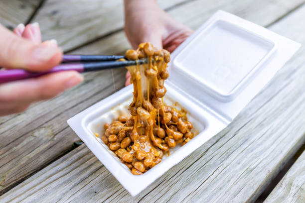 closeup of hand holding chopsticks, mixing asian japanese natto fermented soy dish meal, sticky, slimy texture in styrofoam container box - japanese mustard imagens e fotografias de stock