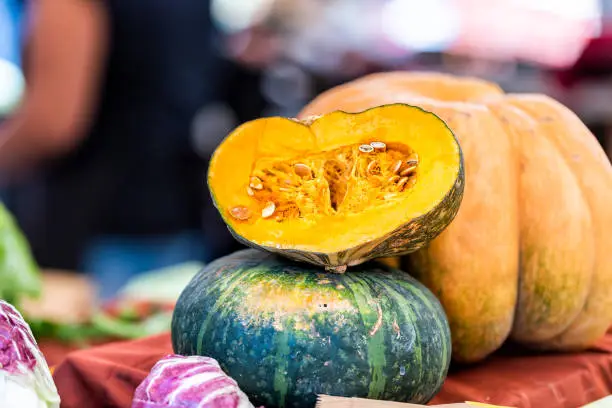 Closeup of cut yellow, orange, green, kabocha pumpkin squash half on display in farm market store in autumn, Japanese vegetable