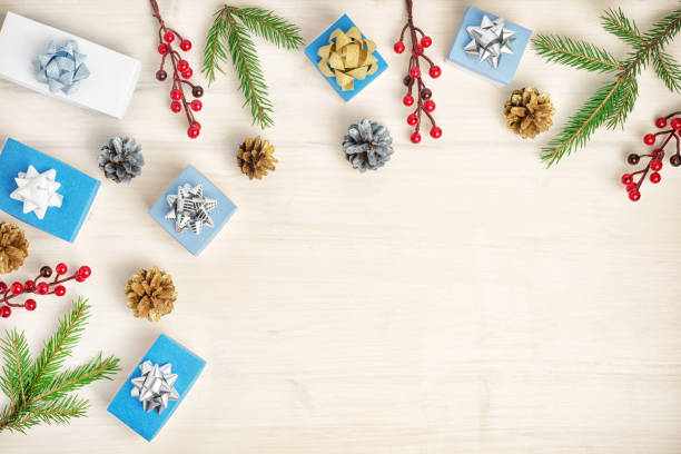 istock Festive light background with copy space. Small gift boxes, fir branches, cones and red berries. Beautiful card. 1059777882