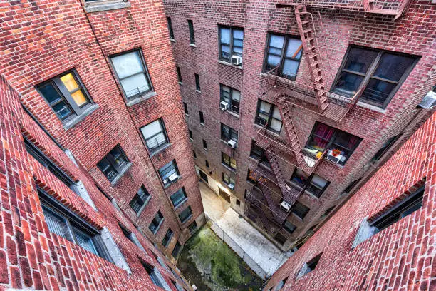 High angle, looking down view on illuminated brick apartment condo building architecture in Fordham Heights center, Bronx, NYC, Manhattan, New York City with fire escapes, windows