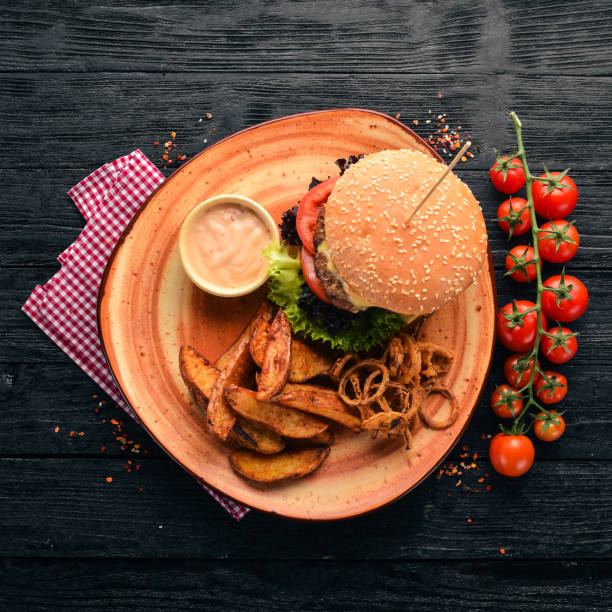Burger with meat, onion, tomatoes and baked potatoes. On the old background. Free copy space. Top view.