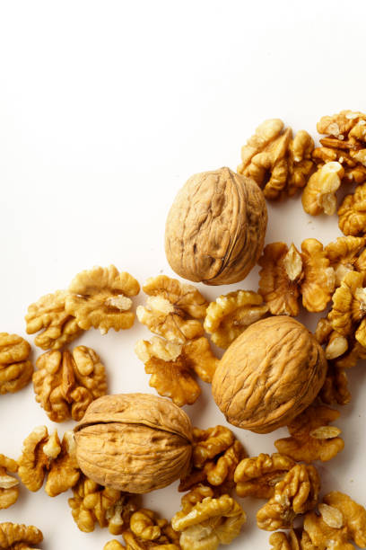 istock Top view of a heap of raw walnuts with a nutshell on white background isolated with copy space 1059781772