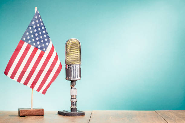 Retro old microphone and USA flag front gradient aquamarine wall background. Vintage style filtered photo Retro old microphone and USA flag front gradient aquamarine wall background. Vintage style filtered photo american propaganda stock pictures, royalty-free photos & images