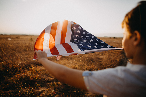 Photo of boy with American flag in nature