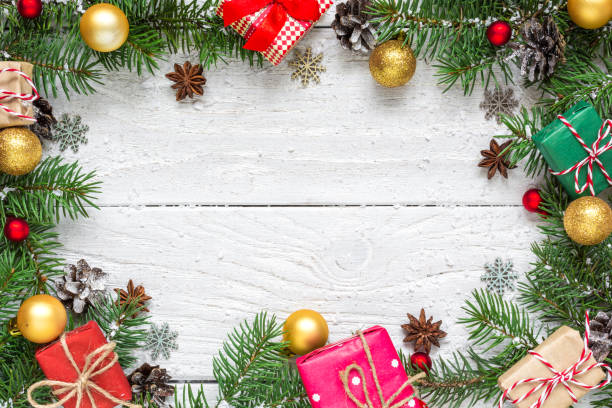 istock Christmas background. frame made of fir branches, gift boxes, decorations and pine cones on white wooden table 1059787512