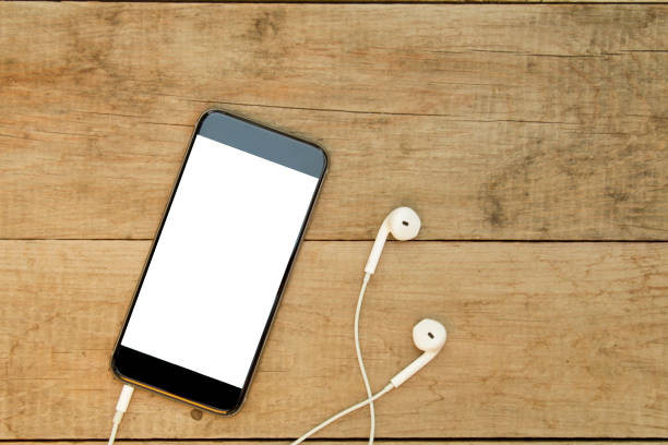 istock Smartphone with headphones on wooden table. 1059792942