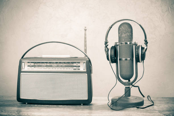 Retro radio and studio ribbon microphone from 50s with headphones on table. Vintage old style sepia photo stock photo