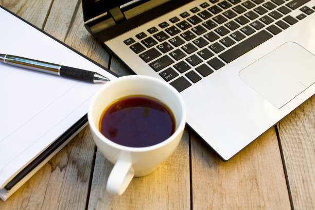 istock Laptop, notebook and coffee cup on wooden table. 1059809884