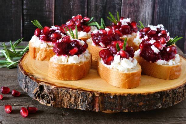 Holiday crostini appetizers with cranberries, pomegranates and feta on a wood log platter Holiday crostini appetizers with cranberries, pomegranates and feta cheese on a rustic wood log platter goat-cheese stock pictures, royalty-free photos & images