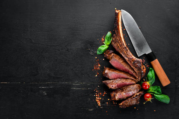 istock Steak on the bone. tomahawk steak On a black wooden background. Top view. Free copy space. 1059835002